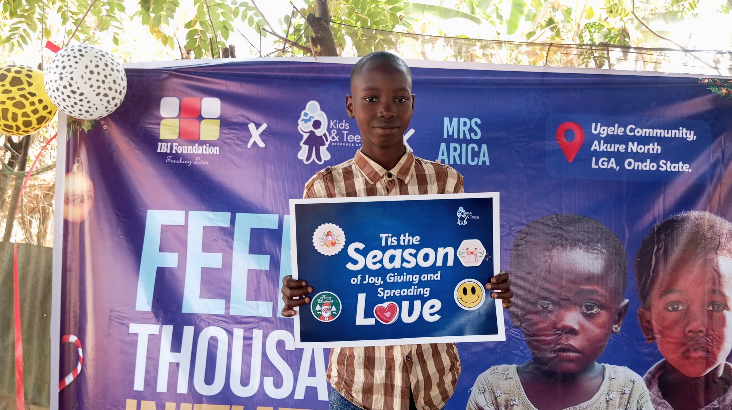 A Boy holding the 'Season of Joy' placard during the FATI Christmas event in Ugele Community, Akure North LGA.