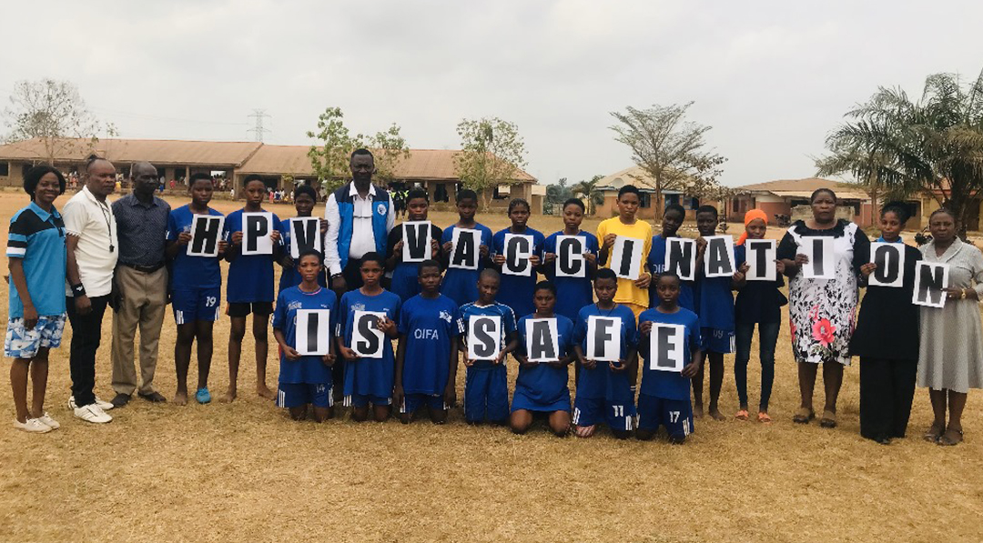 Students at the HPV awareness football match hold signs reading 'HPV Vaccination Is Safe' to promote cervical cancer prevention in Ondo State.
